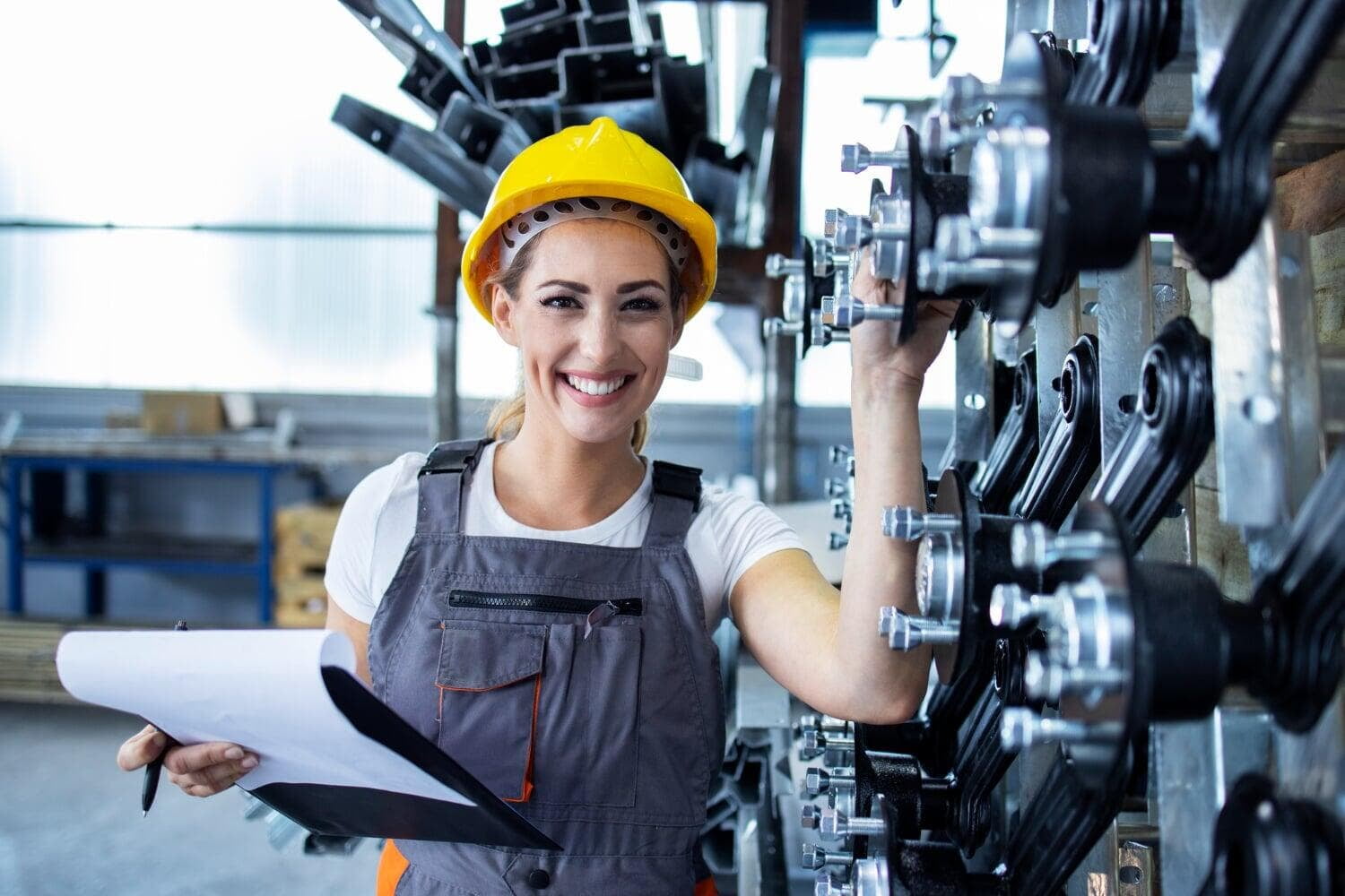 Technician with hard hat and clipboard in a production hall
